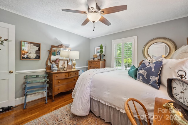 bedroom with crown molding, a textured ceiling, ceiling fan, and wood finished floors