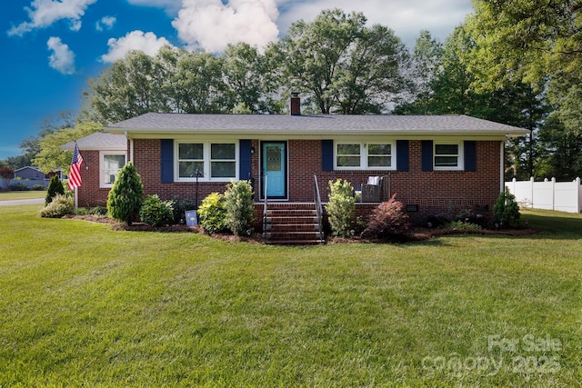 ranch-style home featuring brick siding, fence, and a front yard