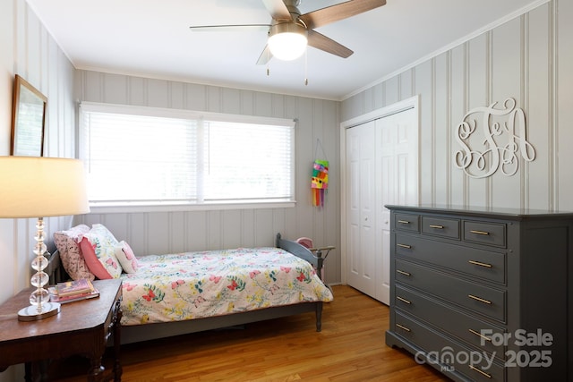 bedroom with crown molding, ceiling fan, a closet, and light wood finished floors