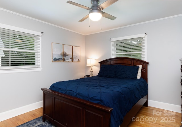 bedroom with baseboards, multiple windows, and wood finished floors