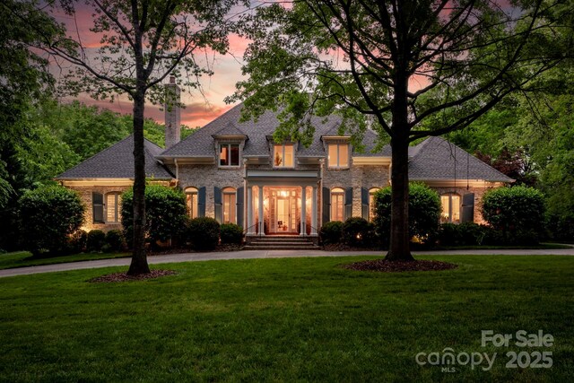 view of front of house featuring a yard, brick siding, and curved driveway