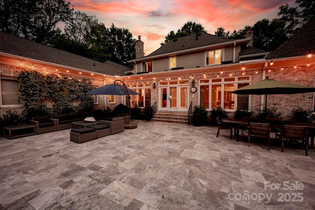 rear view of house featuring french doors, an outdoor living space, a chimney, and a patio area