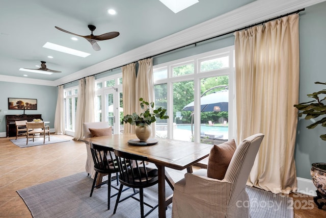 dining area featuring a skylight, light tile patterned floors, crown molding, and a ceiling fan