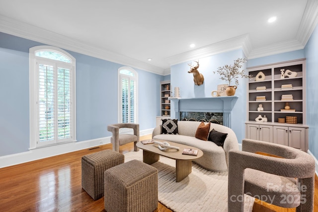 living area with ornamental molding, wood finished floors, baseboards, recessed lighting, and a premium fireplace