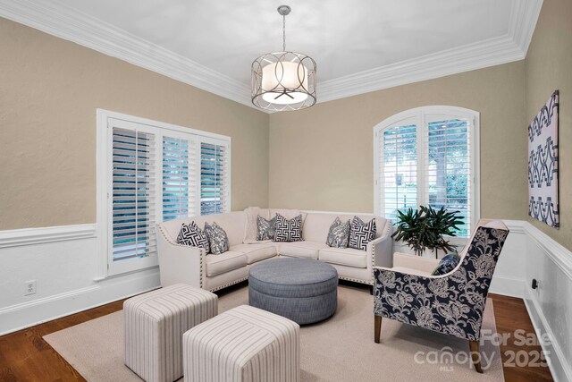 living room with ornamental molding, wood finished floors, and a wainscoted wall
