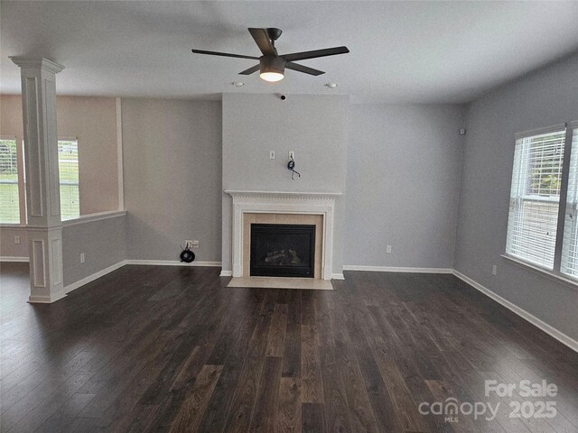 1071 Bassett Way, Fort Mill, SC 29707 - unfurnished living room featuring dark wood-type flooring, a fireplace with flush hearth, a ceiling fan, baseboards, and decorative columns