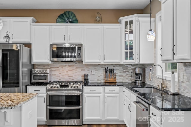 kitchen featuring a sink, appliances with stainless steel finishes, white cabinets, and pendant lighting