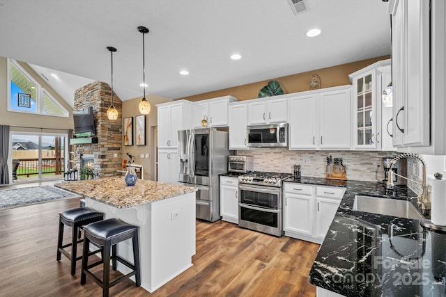 kitchen with visible vents, a center island, white cabinets, tasteful backsplash, and stainless steel appliances
