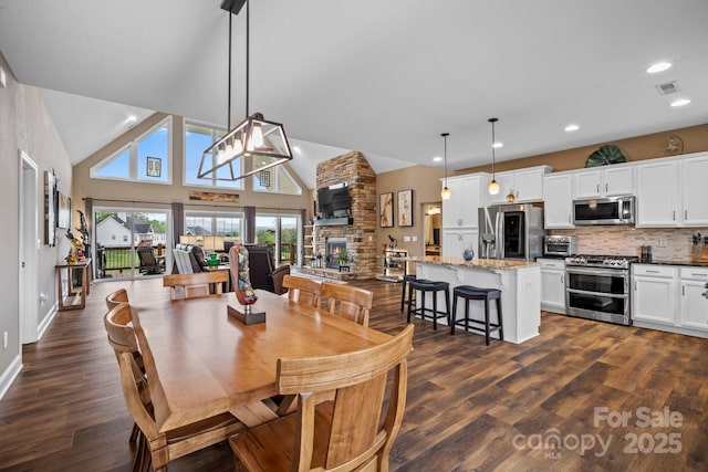 dining room with visible vents, a fireplace, dark wood finished floors, high vaulted ceiling, and recessed lighting