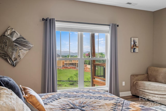 bedroom with visible vents, baseboards, wood finished floors, and a mountain view