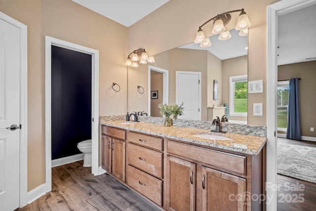 full bath with toilet, baseboards, a sink, and wood finished floors