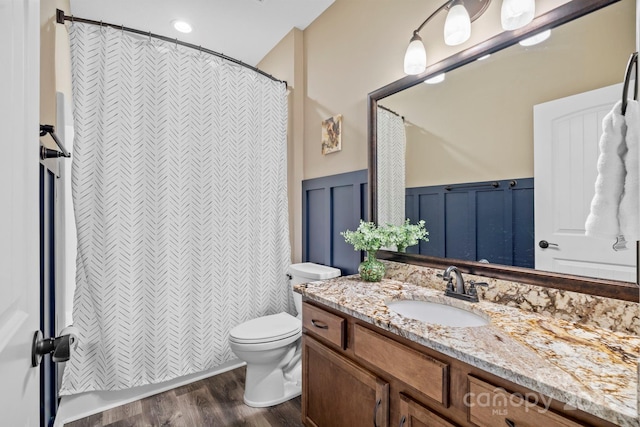 bathroom featuring toilet, curtained shower, wood finished floors, and vanity