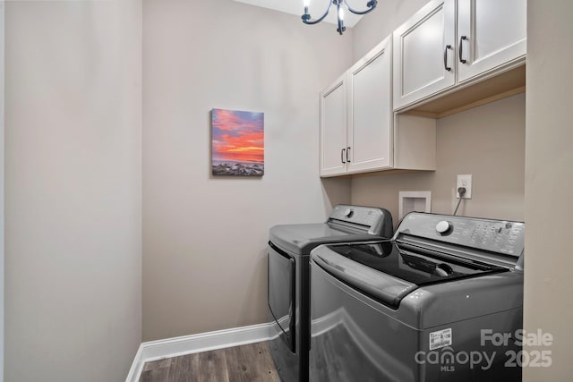laundry area featuring wood finished floors, cabinet space, baseboards, a notable chandelier, and washer and dryer