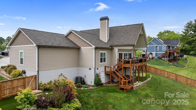 rear view of property featuring a deck, stairway, a fenced backyard, a chimney, and a lawn