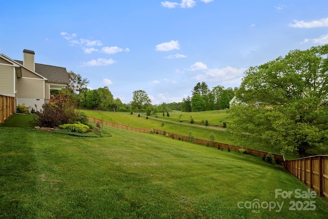 view of yard with fence and a rural view