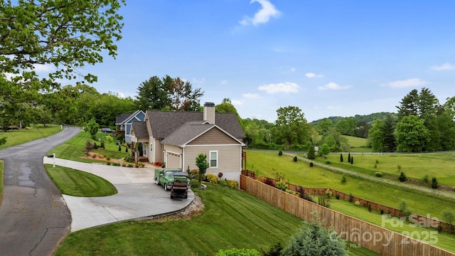 exterior space featuring fence, driveway, a chimney, an attached garage, and a yard