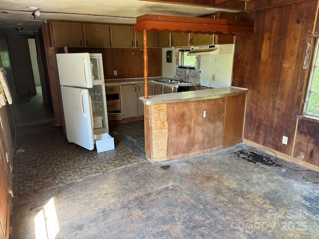 1029 Sullivan St, Wadesboro, NC 28170 - kitchen with freestanding refrigerator, a sink, healthy amount of natural light, wooden walls, and a peninsula