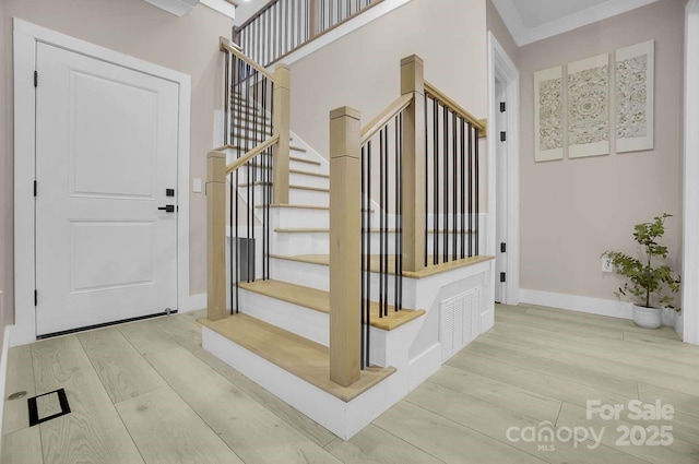staircase with baseboards, visible vents, and wood finished floors