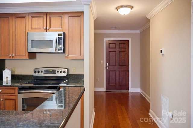 kitchen featuring crown molding, brown cabinetry, stainless steel appliances, baseboards, and dark wood-style floors