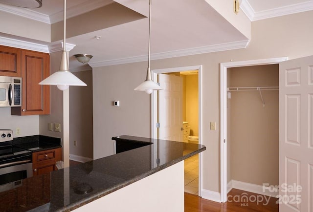 kitchen with ornamental molding, dark wood finished floors, appliances with stainless steel finishes, and brown cabinets