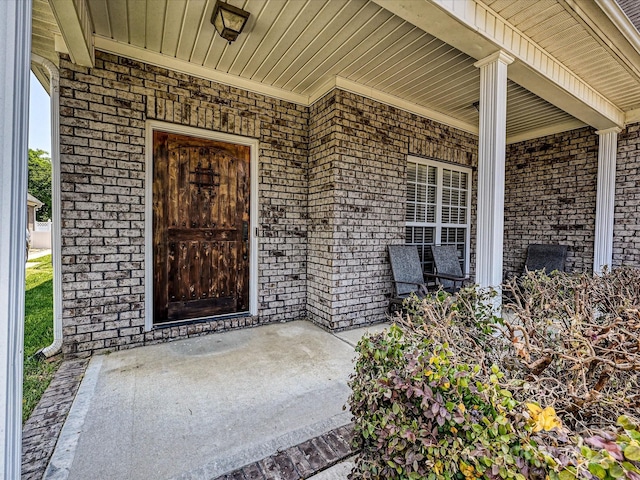 entrance to property featuring covered porch and brick siding