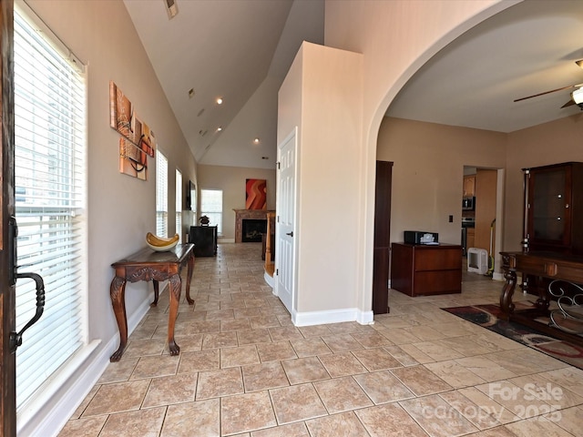 hall with baseboards, arched walkways, vaulted ceiling, and recessed lighting