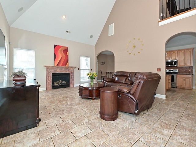 living area featuring arched walkways, high vaulted ceiling, visible vents, and a wealth of natural light