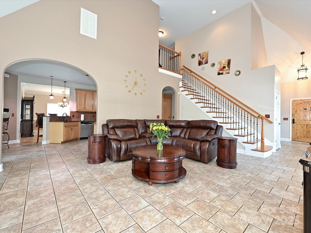 living room featuring arched walkways, baseboards, a towering ceiling, visible vents, and stairway