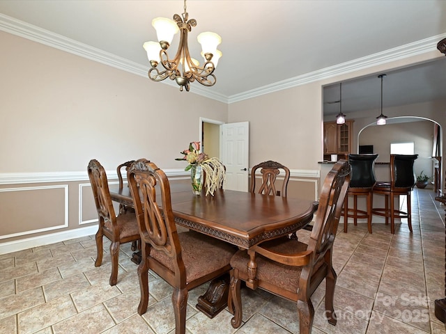 dining room featuring arched walkways, ornamental molding, wainscoting, and a chandelier