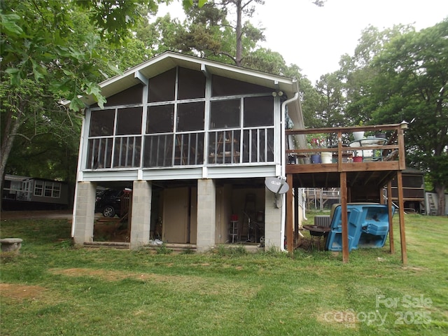 rear view of house with a sunroom, a wooden deck, and a yard