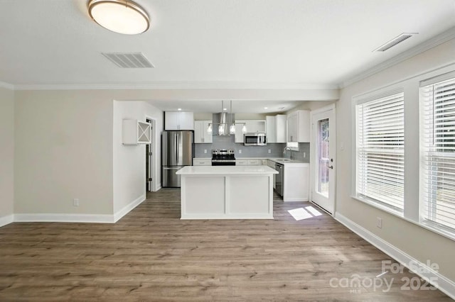 kitchen with appliances with stainless steel finishes, a sink, extractor fan, white cabinetry, and visible vents