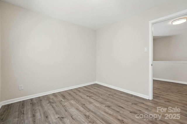 spare room with baseboards and wood finished floors