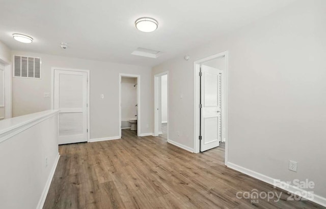 unfurnished room featuring baseboards, wood finished floors, and visible vents