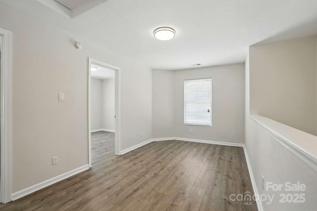 spare room featuring baseboards and wood finished floors