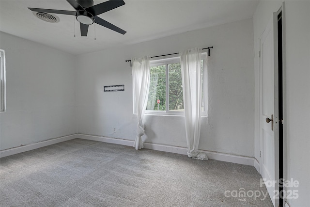 carpeted spare room featuring ceiling fan, visible vents, and baseboards