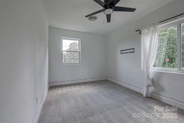 carpeted spare room featuring baseboards, plenty of natural light, ceiling fan, and visible vents
