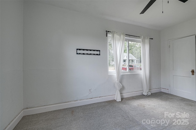 carpeted spare room with baseboards and a ceiling fan