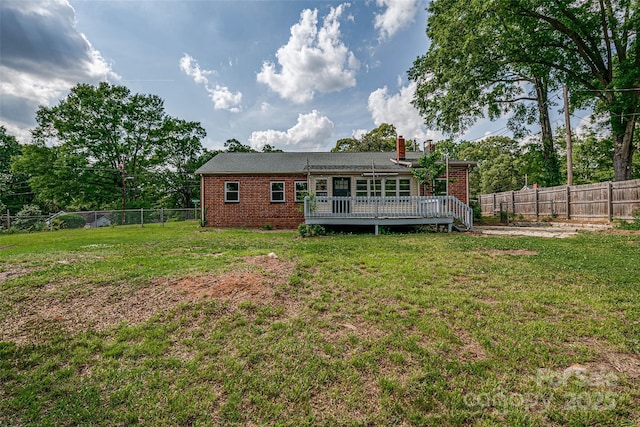 back of house with a fenced backyard, a wooden deck, a lawn, and brick siding