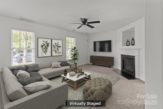 carpeted living room with ceiling fan, a fireplace with flush hearth, and baseboards