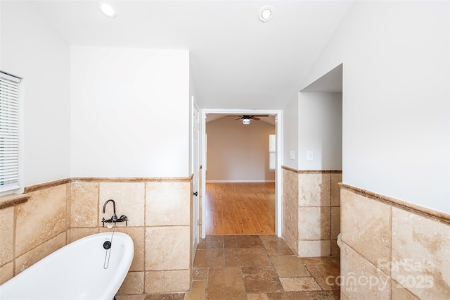 3933 Planters Pl, Indian Trail, NC 28079 - bathroom featuring tile walls, a wainscoted wall, a freestanding bath, ceiling fan, and vaulted ceiling