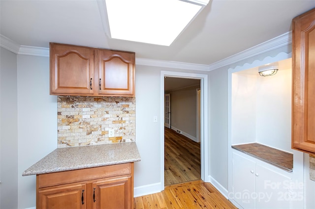3933 Planters Pl, Indian Trail, NC 28079 - kitchen with ornamental molding, tasteful backsplash, light wood-style flooring, and light stone countertops