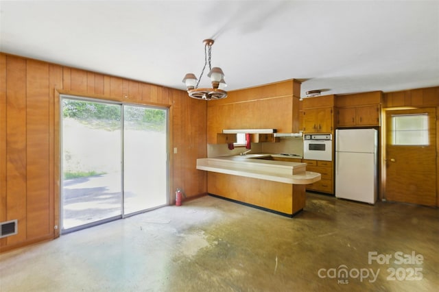 3120 Mineral Springs Mountain Rd, Valdese, NC 28690 - kitchen featuring white appliances, brown cabinetry, concrete flooring, a peninsula, and wood walls
