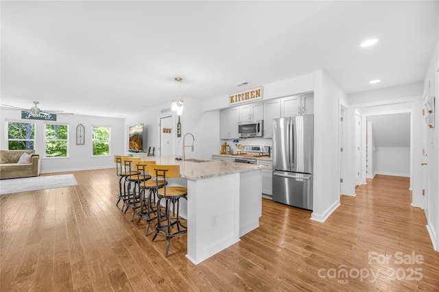 5615 American Way, Denver, NC 28037 - kitchen with a kitchen breakfast bar, appliances with stainless steel finishes, a sink, open floor plan, and light wood-style flooring