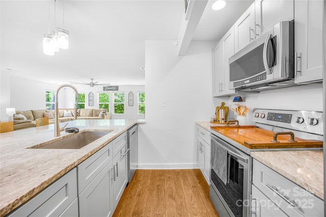 5615 American Way, Denver, NC 28037 - kitchen featuring light wood-style floors, a sink, appliances with stainless steel finishes, and light stone countertops