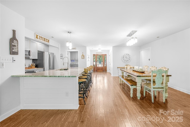 5615 American Way, Denver, NC 28037 - kitchen featuring a kitchen breakfast bar, a sink, light wood finished floors, appliances with stainless steel finishes, and hanging light fixtures