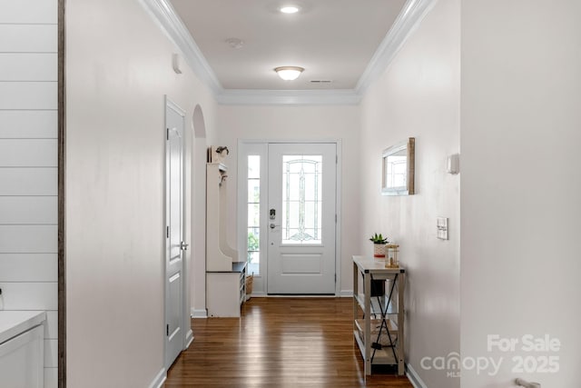doorway with crown molding, arched walkways, baseboards, and wood finished floors