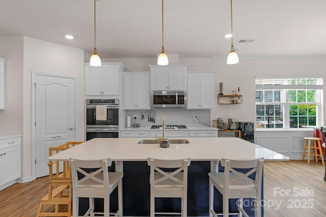 kitchen featuring light countertops, a sink, light wood-style flooring, and stainless steel appliances
