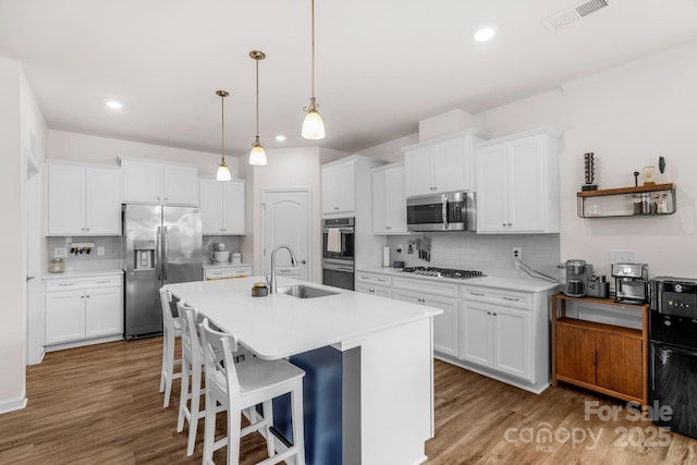 kitchen featuring a sink, backsplash, stainless steel appliances, and visible vents