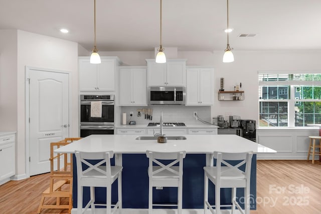 kitchen with visible vents, a sink, appliances with stainless steel finishes, and a breakfast bar