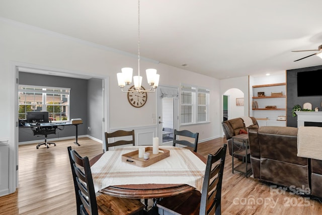 dining space with arched walkways, baseboards, ceiling fan with notable chandelier, and light wood-type flooring